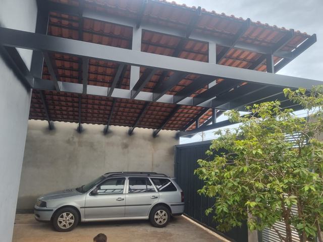 Garagem coberta por estrutura metálica pintada, com telha cerâmica apoiada