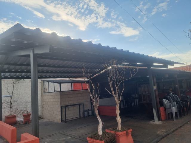 Cobertura de telha ondulada apoiada em pilares metálicos, em fachada comercial