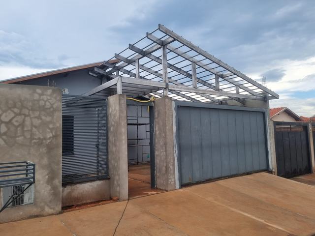 Estrutura metálica de telhado montada sobre garagem, antes do telhamento