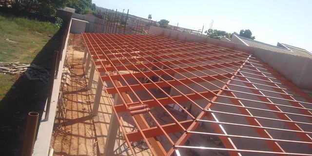 Estrutura metálica de telhado montada em obra, com terças e caibros aparentes