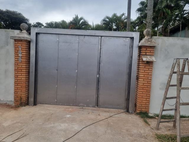 Portão de duas folhas em chapa de aço ainda sem pintura, recém-instalado